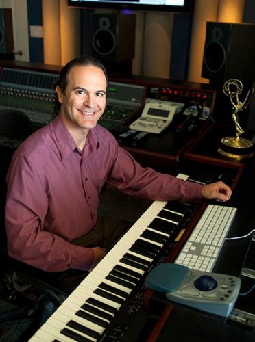 Photo of Kristopher Carter at an electric piano. His grammy is visible in the background.