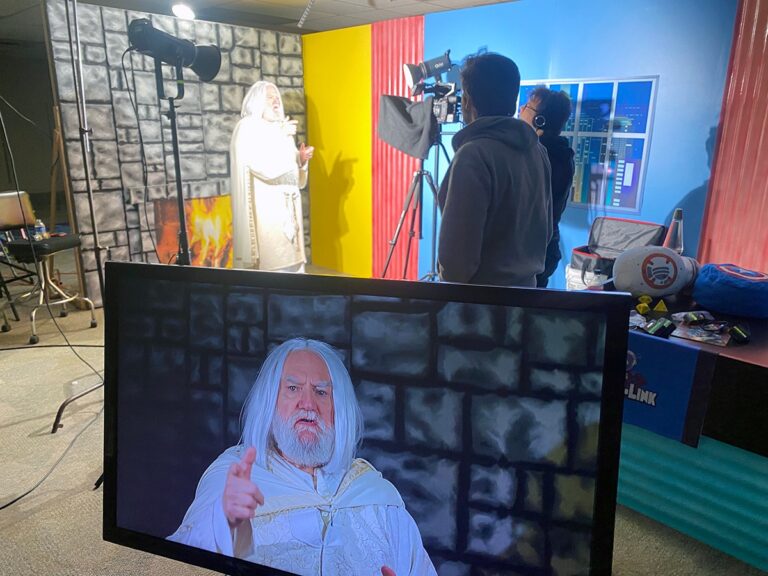 A CVG-TV video shoot with a gandalf cosplayer up on the monitor and volunteer camera operators in the background