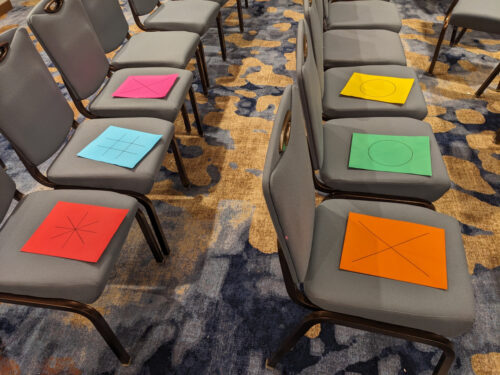 Colored cards with shapes on chairs in CONvergence panel room
